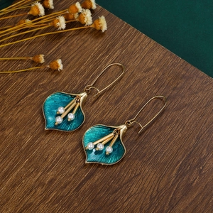 Detailed view of enamel calla lily earrings with white pearls and gold hooks