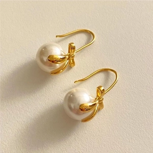 Detail shot of 925 silver bow-knot earrings with round white pearls and gold plating