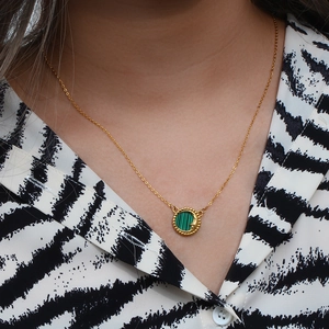 Close-up of gold chain necklace with a green malachite pendant featuring moon and star motifs