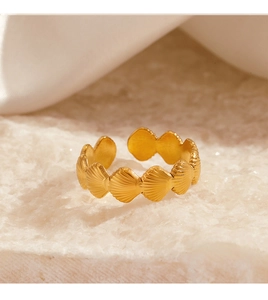 Detail of 18K gold-plated stainless steel shell texture ring on a beige stone surface