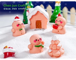 Close-up of miniature Christmas gingerbread man figurines and snowy resin house decor