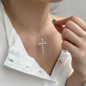 Close-up of S925 sterling silver cross necklace with inlaid white pearls on a model