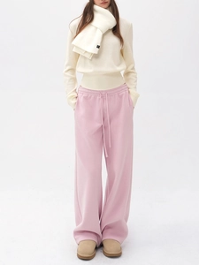 Vue détaillée du pantalon rose associé à un pull en maille et une écharpe crème