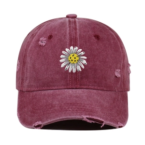 Close-up of distressed wine red baseball cap with daisy embroidery and vintage fraying