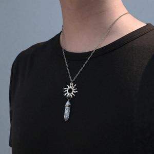 Silver sun pendant necklace with white hexagonal stone column on black t-shirt
