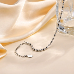 Macro shot of silver football bead chain bracelet with K18 tag on champagne silk cloth