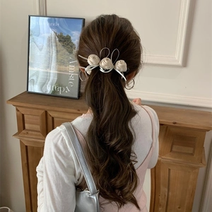Pince à cheveux banane avec rose blanc cassé pour femme portée sur cheveux bouclés