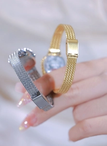 Detail of elegant mesh watch straps with secure folding clasps in gold and silver finish