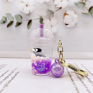 Detail of a mini milk tea cup keychain featuring purple liquid sand and a cute penguin inside