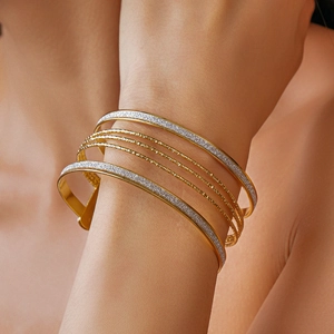 Close-up of multilayered gold and silver bangles with glitter finish on a wrist
