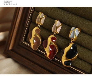 Detail view of irregular geometric enamel earrings with molten gold texture on green velvet