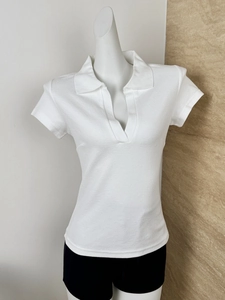 Detail shot of the white polo shirt showing textured fabric and V-neck lapel design
