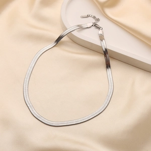 Flat silver stainless steel herringbone chain necklace on elegant satin background