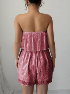Dettaglio della tuta rosa senza spalline con elegante tessuto jacquard floreale e retro