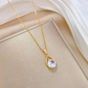 Elegant gold titanium steel teardrop necklace with round clear gemstone on beige box