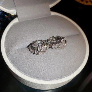 Macro view of silver snake-shaped cuff earrings with zircon scales on velvet jewelry box