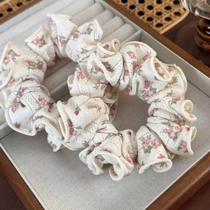 Close-up of two floral scrunchies with pink flower patterns in a wooden jewelry box