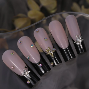 Detailed view of pink and black gradient fake nails with mini star charms and rhinestones