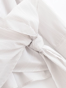 Detailed close-up of vertical black stripes and decorative waist knot on white shirt