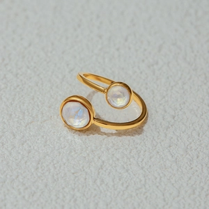 Macro detail of gold-plated open ring featuring two symmetric white faceted opal stones