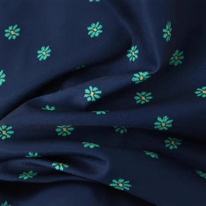 Detail of dark blue summer dress fabric featuring small green floral print and soft texture