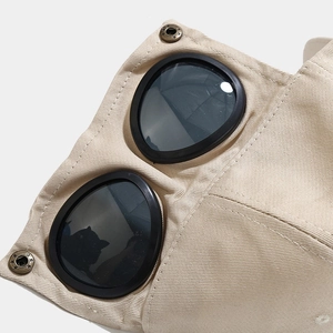 Macro detail of khaki twill cotton cap with dark goggles and vintage metal buttons