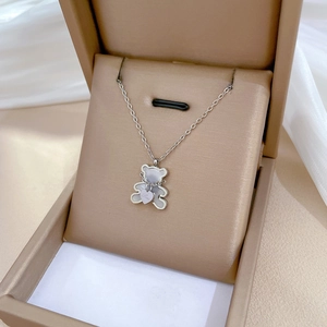 Close-up of titanium steel bear necklace with mother-of-pearl inlay in a beige jewelry box