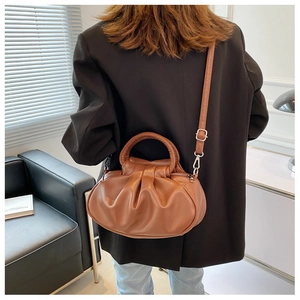 Brown ruched cloud bag with top handle and adjustable strap shown on a model