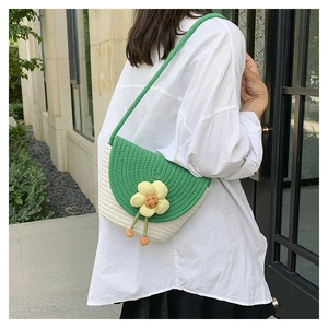Detalle de bolso tejido de semicírculo con adorno de flor 3D y correa verde larga
