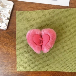 Detailed view of a pink plush heart-shaped hair claw clip with faux fur texture