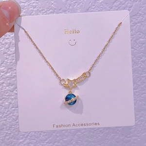 Dettaglio ravvicinato di una collana dorata a forma di pianeta con stella e ciondolo blu orbitale