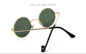 Detail view of round metal sunglasses with gold frame and green lenses at 45-degree angle