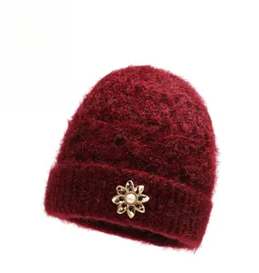 Close-up of wine red knit hat for elderly women with golden flower and pearl decoration
