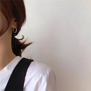 Close-up of twisted 925 sterling silver hoop earring on model showing minimalist texture