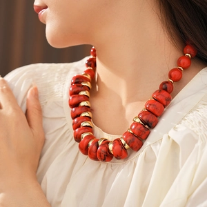 Détail d'un collier bohème vintage avec grosses perles rouges et accents dorés
