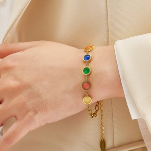 Detail of colorful gemstone bracelet on model wrist with gold links and extension chain