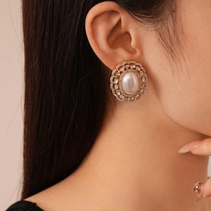 Close-up of vintage oval pearl earrings with sparkling rhinestones on the model's ear