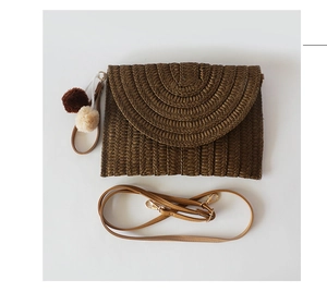 Detail of dark brown straw clutch featuring textured weave and colorful pompom charms