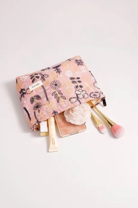 Detail of pink floral embroidered fabric cosmetic bag with gold zipper and makeup tools