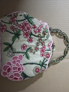 Macro shot of pink and green floral beadwork on a vintage linen handbag with metal handle