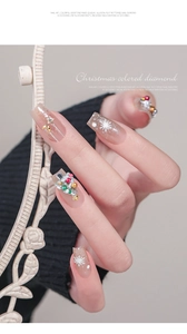 Detailed view of Christmas nail art charms with snowflakes, trees and stars on fingernails