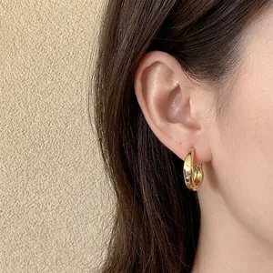 Minimalist thick gold C-shaped hoop earrings with polished finish worn by a model