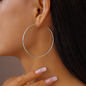 Close-up of polished silver C-shaped hoop earrings on a model for a minimalist look