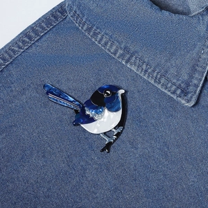 Acrylic blue and white magpie bird brooch pinned on a classic denim jacket lapel