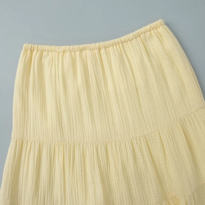 Detail of light yellow tiered skirt featuring elastic waistband and crinkle cotton fabric