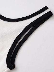 Detailaufnahme des weißen Strickoberteils mit schwarzer Paspelierung und feinen Nähten