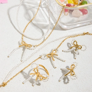 Detailed top view of gold bow and pearl jewelry set with necklace and bracelet