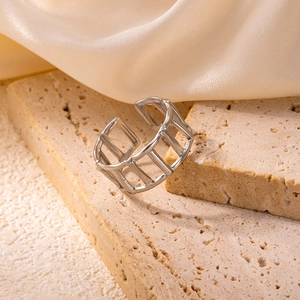 Detail of silver geometric hollow ring on elegant silk and stone background