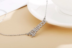 Macro shot of silver titanium pendant with BLESSED gothic engraving on a thin chain