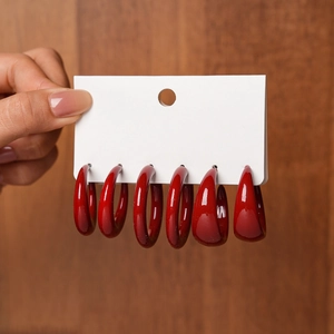 Detailed view of six vintage glossy red acrylic C-shaped earrings on a display card